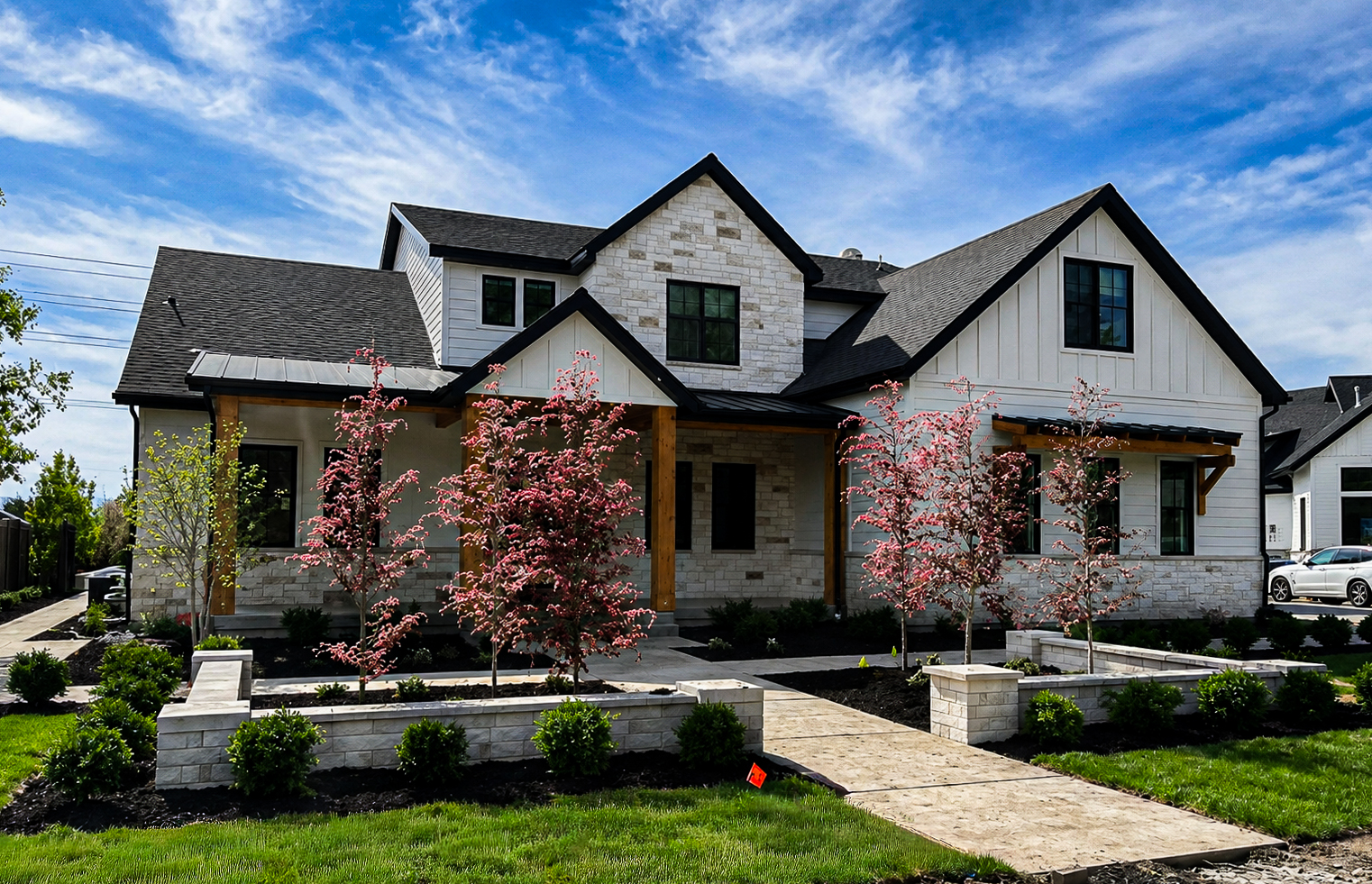 White farmhouse with stone accents, a paver front walkway and stone retaining walls, walkways & entryways by Empire Pavers in Utah